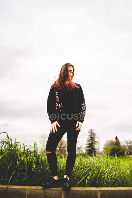 Woman standing on brick wall in countryside — Stock Photo