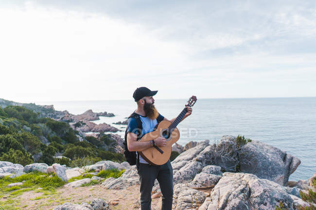 Homme jouant de la guitare sur la côte — Photo de stock