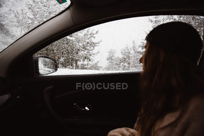 Frau sitzt im Auto im Winterwald — Stockfoto