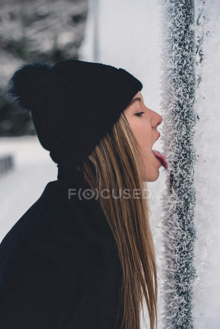 Frau leckt gefrorene Stange — Stockfoto
