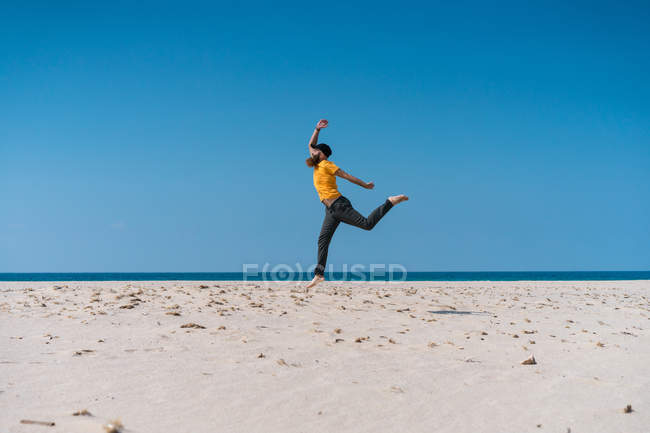 Homem pulando na praia arenosa — Fotografia de Stock