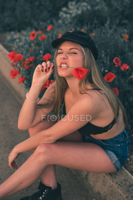 Femme en soutien-gorge noir mordant fleur — Photo de stock
