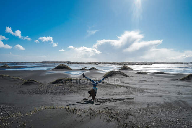 Девушка делает сосну на песчаном пляже — стоковое фото