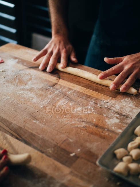 Hands making cylinder with dough — Stock Photo