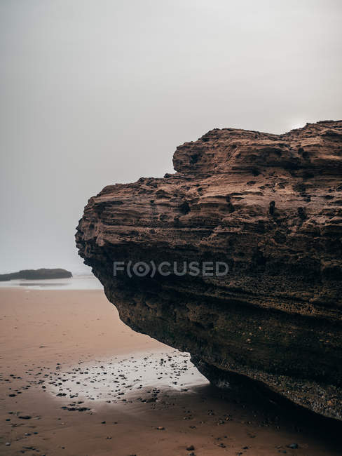 Grande roccia sulla costa sabbiosa — Foto stock