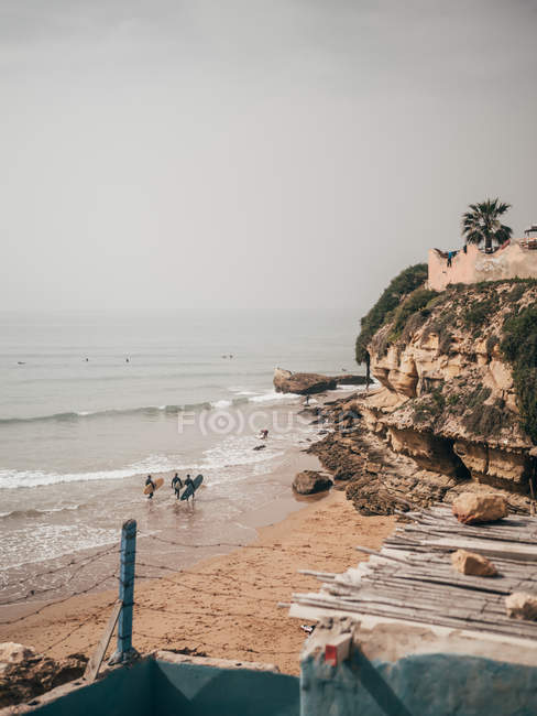 Surfistas caminando en la playa de arena - foto de stock