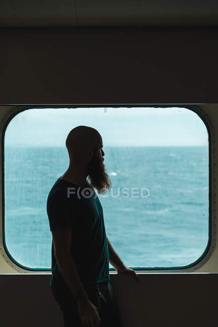 Человек, стоящий у окна на корабле — стоковое фото