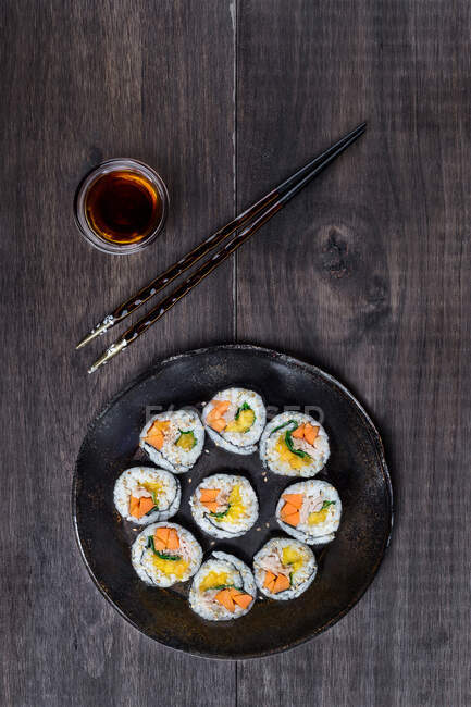 De arriba sushi hosomaki servido con palos y salsa de soja en la mesa. - foto de stock