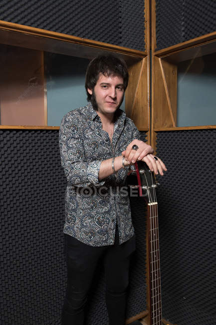 Hombre de pie con guitarra en el estudio - foto de stock