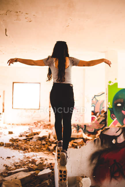 Mujer caminando en pared dañada - foto de stock