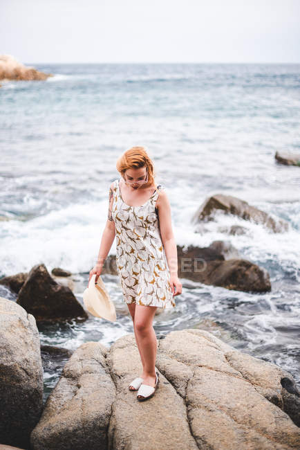 Donna con cappello in piedi sulla roccia — Foto stock
