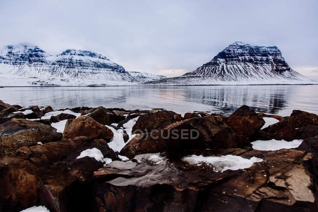 Lago con rocas y montañas nevadas - foto de stock