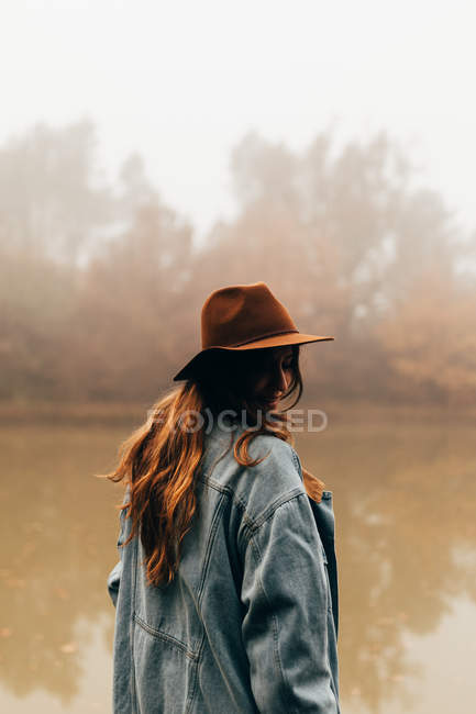 Mujer usando sombrero de pie en el estanque - foto de stock