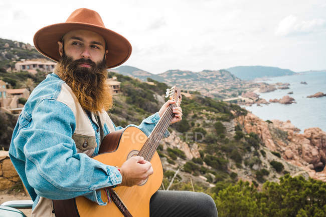 Людина грає на гітарі на морському узбережжі — стокове фото