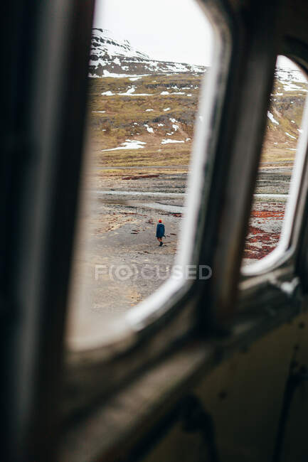 Vista dalla vecchia finestra di persona passeggiando da solo su un terreno roccioso grigio con montagne sullo sfondo in Islanda. — Foto stock
