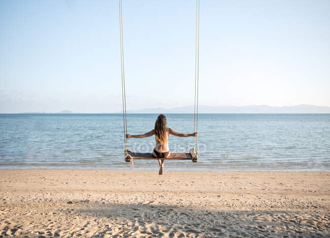 Donna rilassante sulle altalene sulla spiaggia — Foto stock