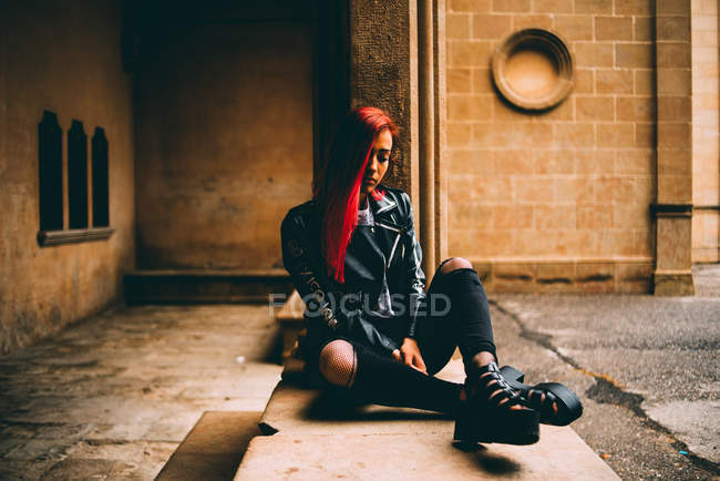 Trendy woman sitting on old gallery — Stock Photo