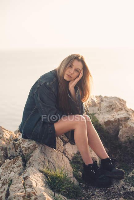 Frau sitzt auf Felsen und blickt in Kamera — Stockfoto