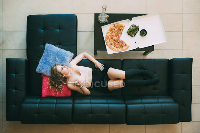 Femme couchée sur le canapé avec joint de marijuana — Photo de stock