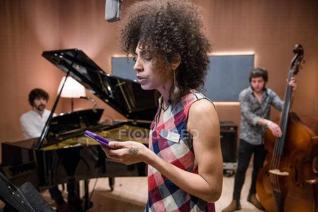 Співачка перевіряє смартфон під час репетиції — стокове фото