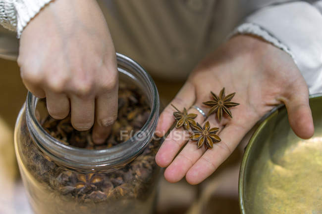Female hands taking anise from jar — Stock Photo
