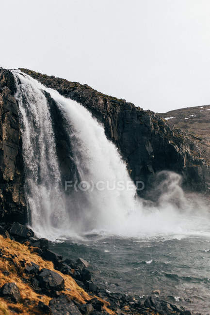 Waterfall rushing down from rocky cliff — Stock Photo