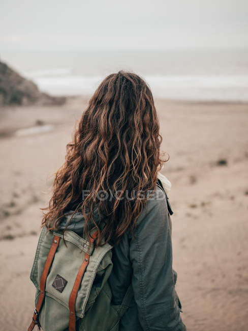 Женщина с рюкзаком стоит у океана — стоковое фото