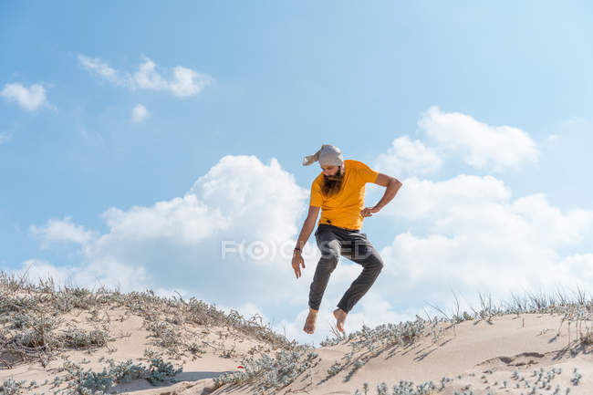 Чоловік стрибає на піщаному пагорбі — стокове фото