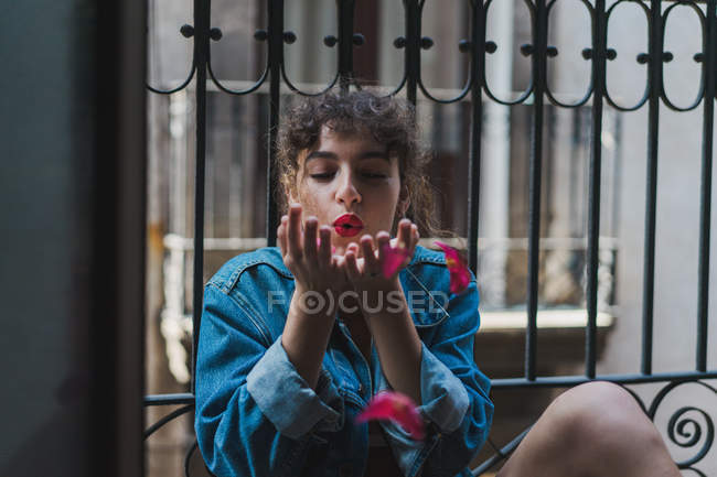 Donna soffiando petali di rosa via — Foto stock