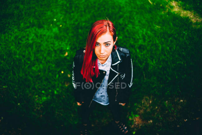 Жінка з червоним фарбованим волоссям, що стоїть на траві — стокове фото