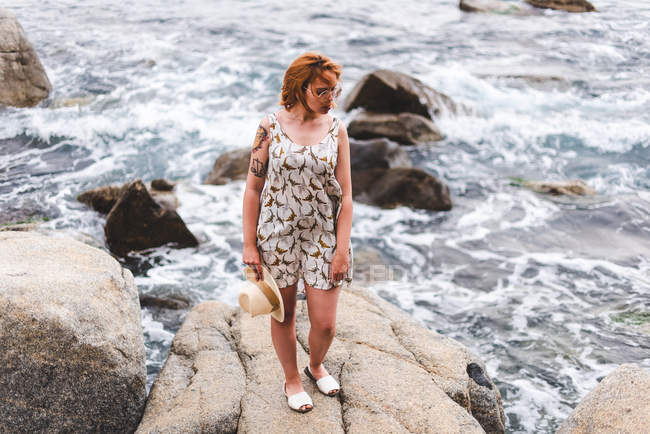 Donna con cappello in piedi sulla roccia — Foto stock