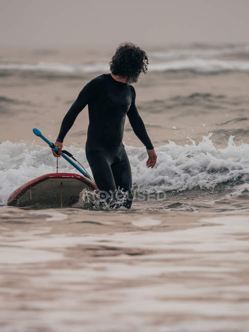 Homme avec planche à pagaie dans l'océan — Photo de stock