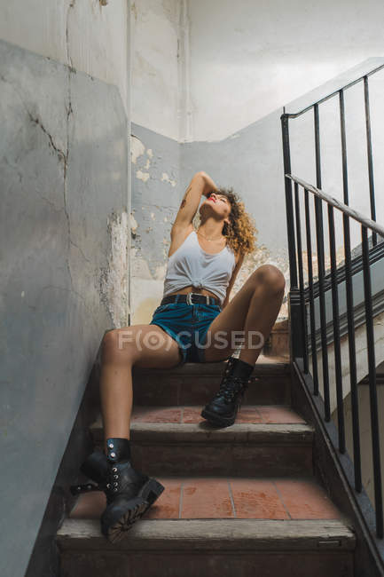 Woman sitting on shabby steps — Stock Photo