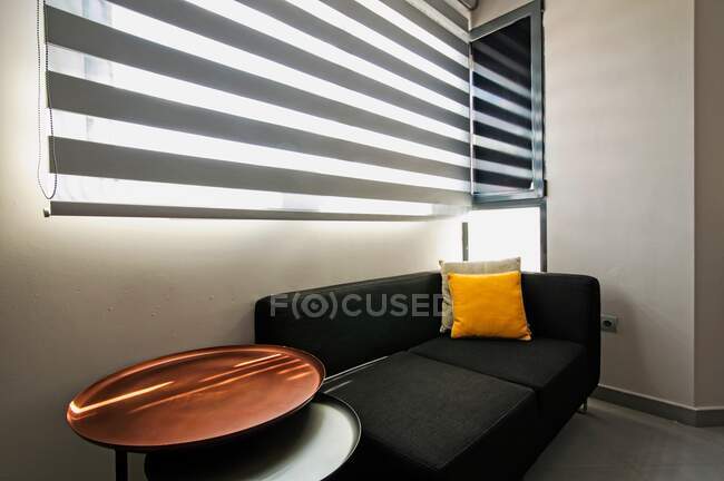 Комфортний диван і невеликий стіл, що стоїть біля вікна в стильній кімнаті . — стокове фото