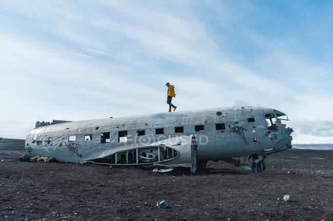 Giovane uomo che cammina sulla carcassa di aerei abbandonati mentre viaggia attraverso l'Islanda — Foto stock
