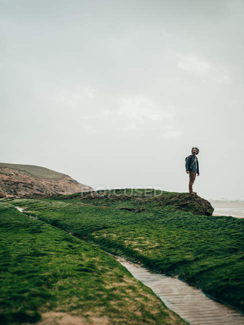 Mann steht auf grünem Stein am Meer — Stockfoto
