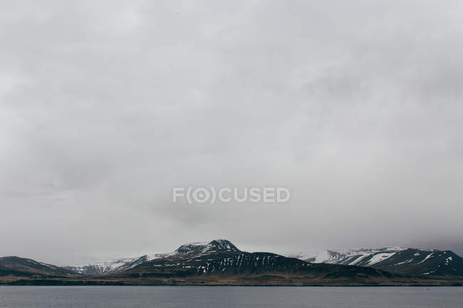 Gloomy clouds above snowy range of mountains — Stock Photo
