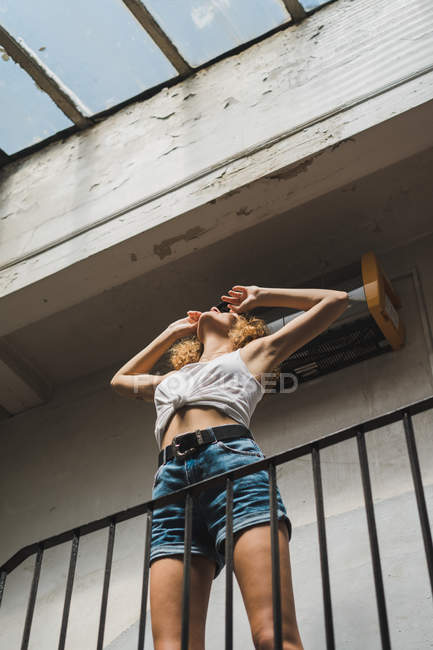 Stylish woman standing in shabby hall — Stock Photo