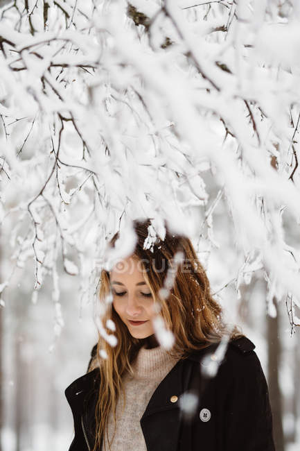 Frau steht zwischen winterlichen Ästen — Stockfoto