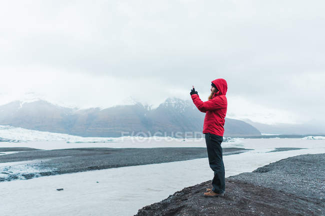 Человек фотографируется со смартфоном в природе — стоковое фото