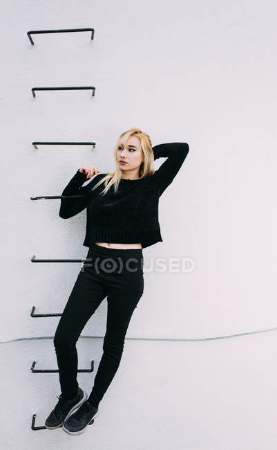 Mujer de pie en escalera en la pared - foto de stock