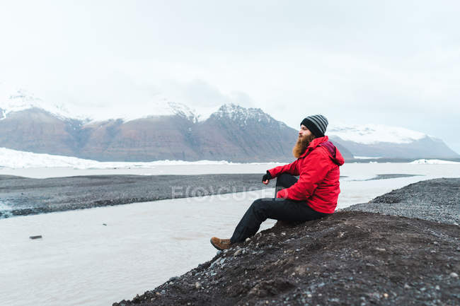 Hombre sentado cerca del agua en las montañas - foto de stock