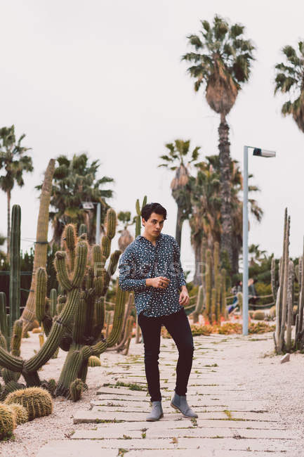 Hombre parado en el cactus en el jardín - foto de stock