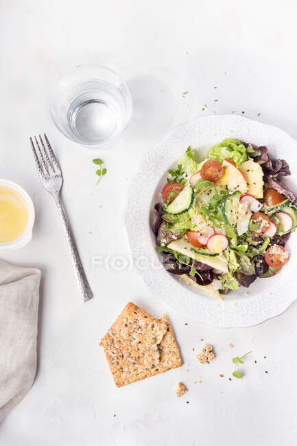 Зверху смачний свіжий овочевий салат, поданий з крекерами на білому столі . — стокове фото
