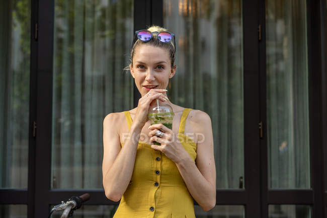 Woman in summer dress standing with drink — Stock Photo