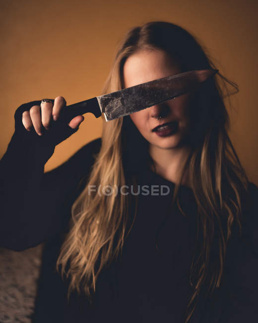 Mujer rubia cubriendo los ojos con cuchillo - foto de stock