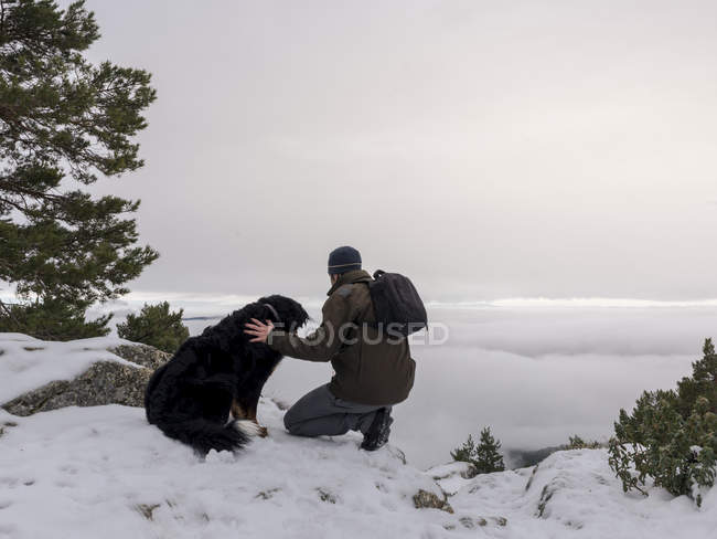 Senderista y perro en montañas nevadas - foto de stock