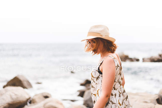 Woman with hat standing at sea — Stock Photo