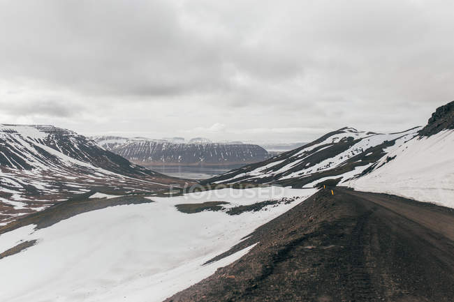 Estrada rural através de montanhas nevadas — Fotografia de Stock