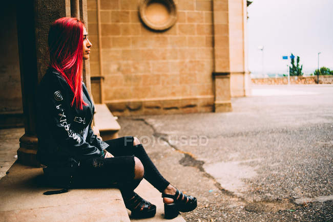 Trendy woman sitting on old gallery — Stock Photo